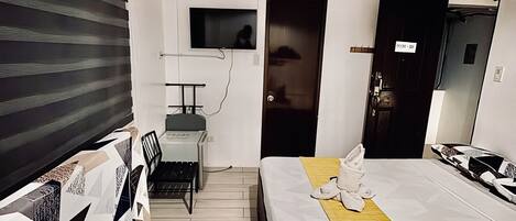 A hotel room with a bed, a desk, a chair, a TV, and a door labeled 'ROOM 201'.