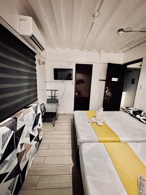 Een hotelkamer met een bed, een bureau, een stoel, een televisie en een deur met de tekst 'ROOM 201'.