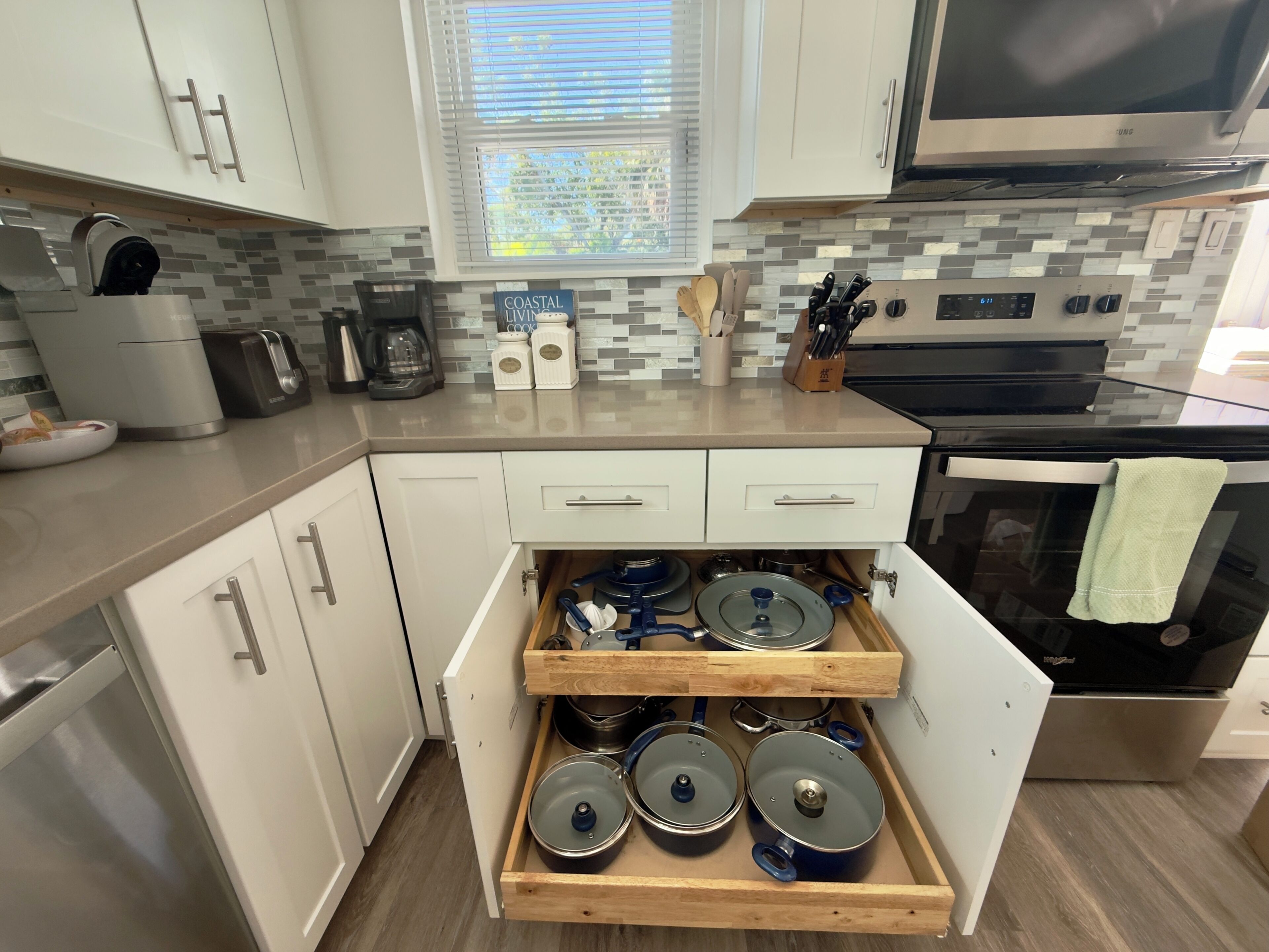 A modern kitchen with white cabinets, a built-in oven, and a microwave.