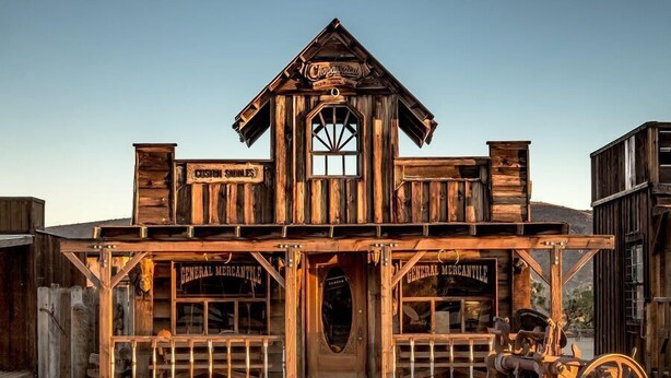 A wooden building with signs reading "Custom Saddles" and "General Mercantile".