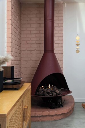 A modern fireplace with a brick wall backdrop, a wooden cabinet, and a record player. - Flamingo Social Club • Boutique Luxury, Romantic Hot Tub with Fireplace (Yucca Valley)