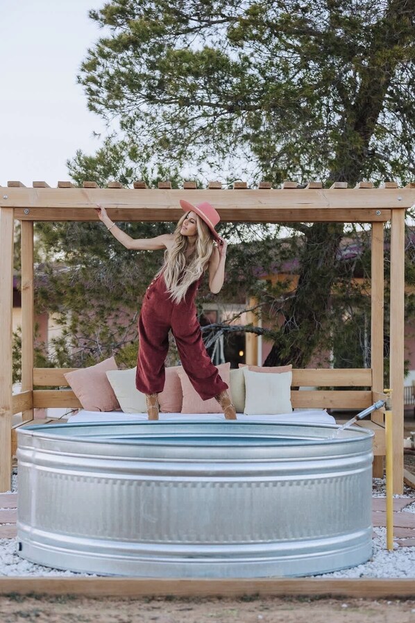 A person standing on a wooden deck with a metal barrel in the foreground. - Flamingo Social Club • Boutique Luxury, Romantic Hot Tub with Fireplace (Yucca Valley)