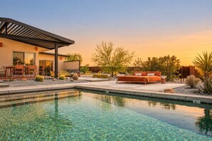 A modern outdoor pool area with clear water, a covered seating area, and a lounge chair. - JT Improper · Saltwater Pool, Hot Tub, 10 Acres (Joshua Tree)
