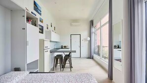 A modern, compact living space with a kitchenette, a dining area, and a large window offering a view. - Romantic studio with terrace overlooking the lake. (Lezzeno)