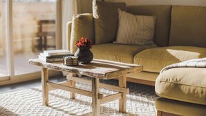 A cozy living room with a wooden coffee table, a sofa, and a window with a view.