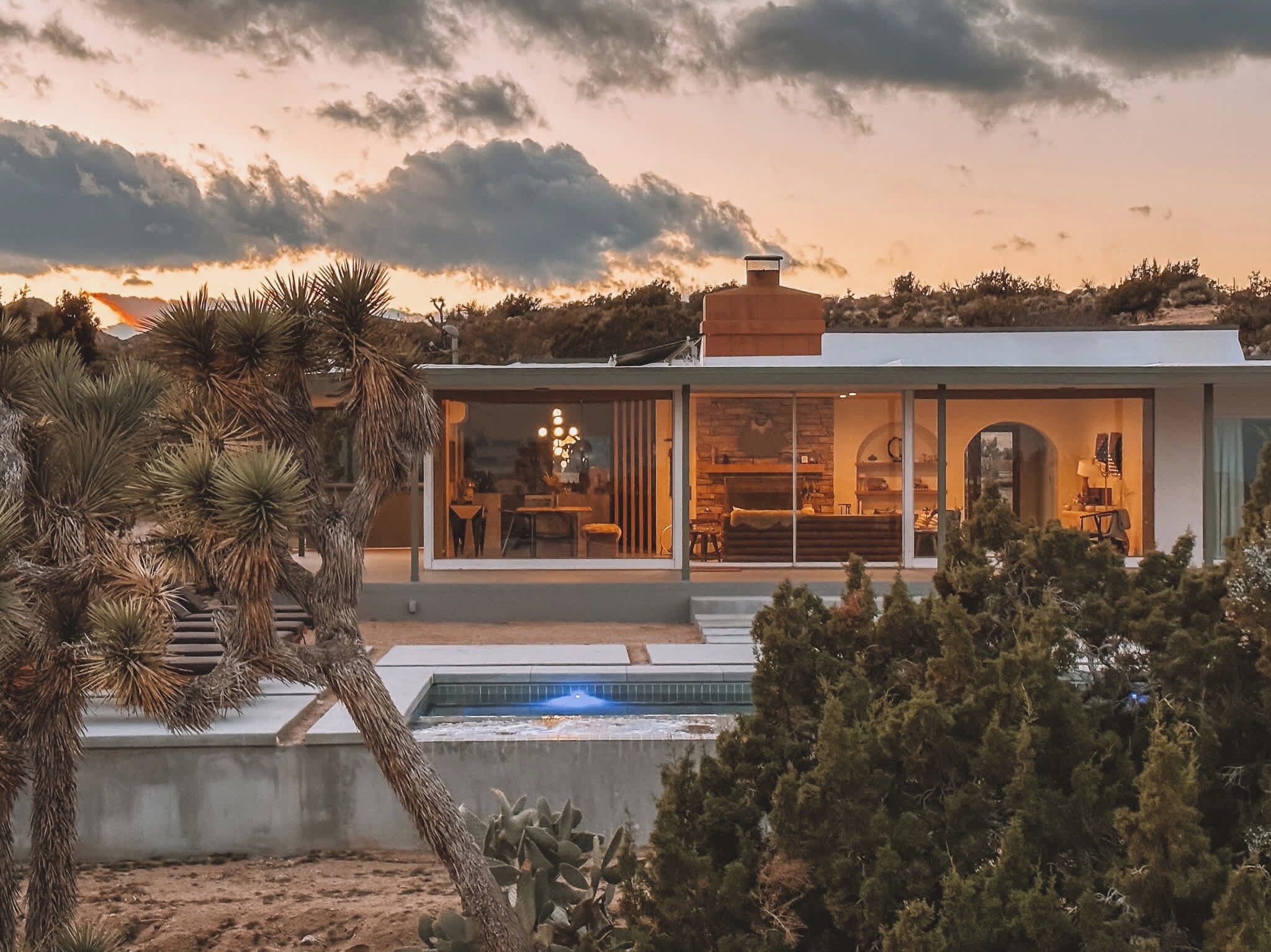 Uma casa moderna com piscina, rodeada por vegetação desértica.