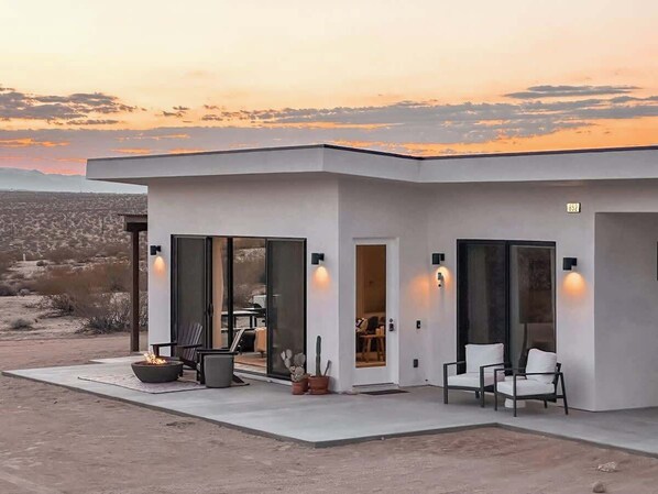 A modern house with a patio, outdoor seating, and a fire pit. - Noetic House · Hot Tub, Cowboy Tub, Views, 5 Acres (Joshua Tree)