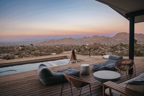 Eine Holzterrasse mit Sitzgelegenheiten im Freien, einem Whirlpool und einem Pool.