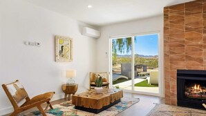 Una sala de estar moderna con chimenea, un ventanal grande y vistas al exterior.