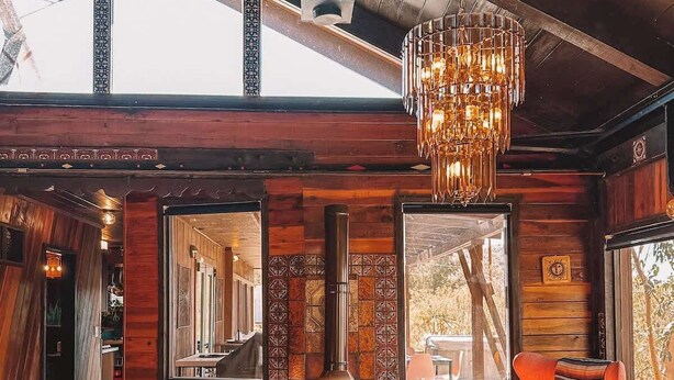Un accogliente soggiorno con camino, divano in pelle e lampadario moderno.