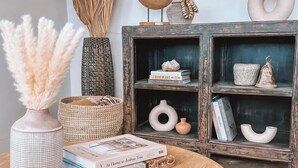 Una mesa de madera con un florero, libros y objetos decorativos.