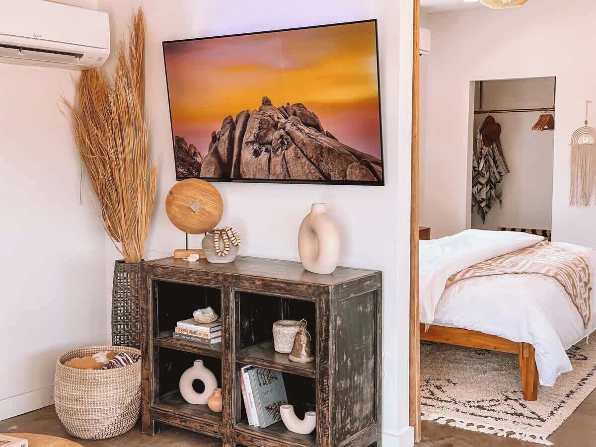 Ein Schlafzimmer mit einem Bett, einem Nachttisch, einem an der Wand montierten Fernseher und einem Bücherregal.
