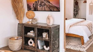 Un dormitorio con cama, una mesita de noche, un televisor montado en la pared y una estantería.