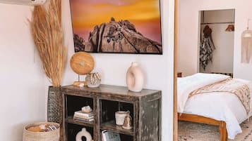 Ein Schlafzimmer mit einem Bett, einem Nachttisch, einem an der Wand montierten Fernseher und einem Bücherregal.