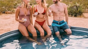 Three people sitting in a swimming pool with a desert landscape in the background. - Starship Landing • 2 Epic Houses Retreat, 10 Acres (Yucca Valley)