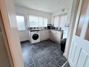 A compact kitchen with a washing machine, a sink, and a microwave. - Toast Stays - The Stray Space (Darlington)