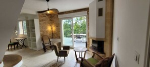Een moderne woonkamer met een open haard, een eethoek met een tafel en stoelen, en een balkon met tuinmeubilair.