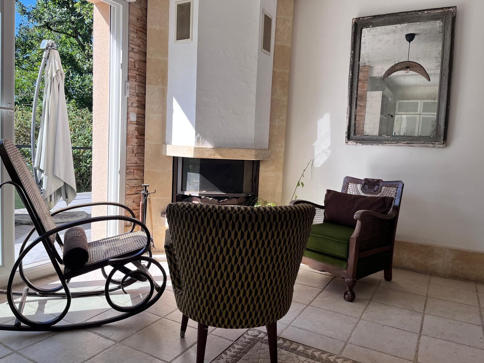 Ein Wohnzimmer mit Kamin, Schaukelstuhl, Sofa und Esstisch.