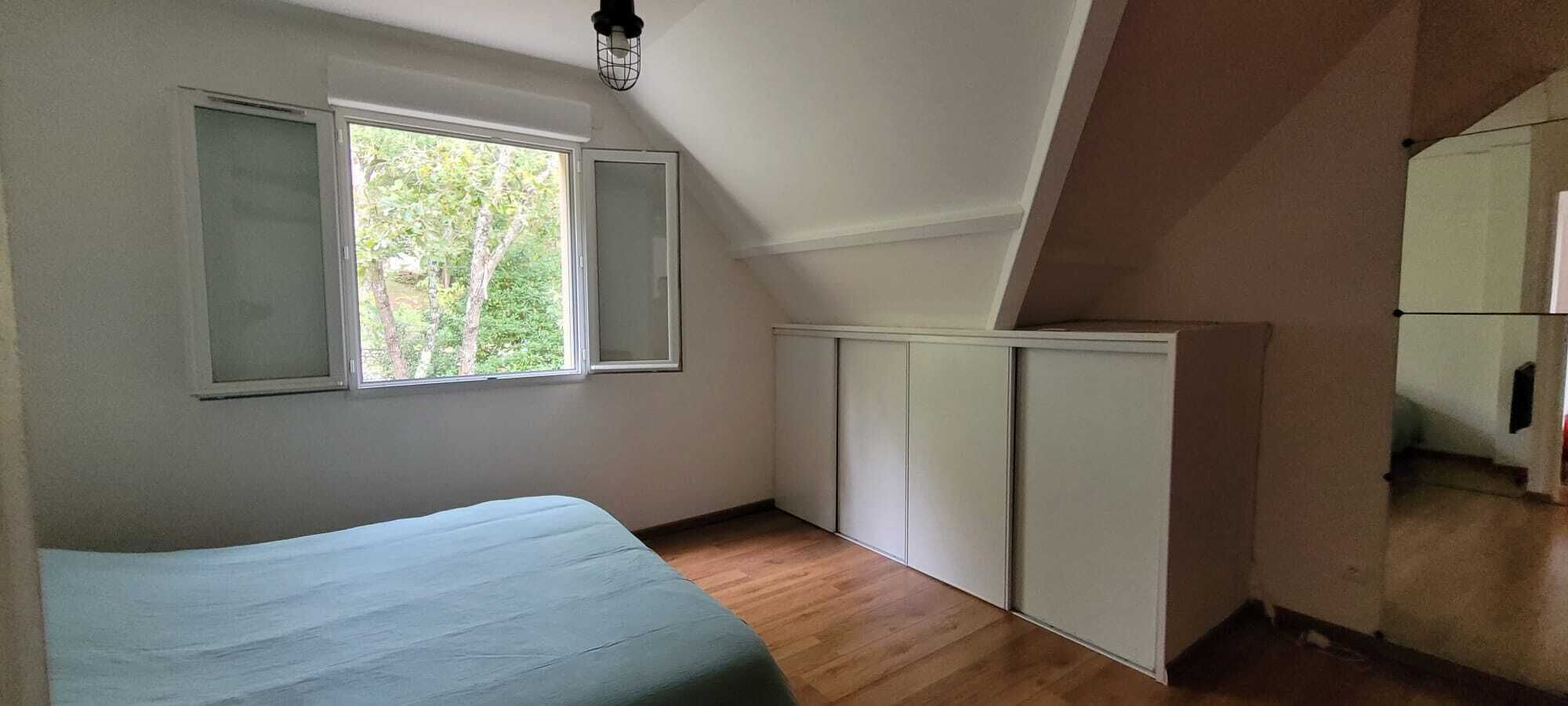 Una stanza piccola e luminosa con un letto, una finestra e un armadio bianco.