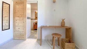 Una stanza minimalista con una scrivania in legno, uno sgabello e un cesto intrecciato.
