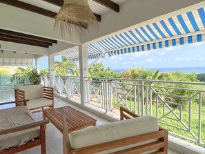 A covered outdoor seating area with a view of the ocean. - Villa Caméo • Grande villa familiale vue mer 180° (Le Gosier)