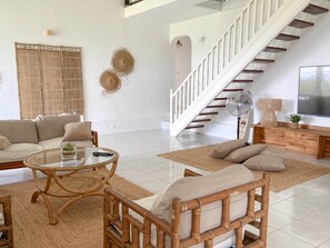 A spacious living room with a white staircase, a glass coffee table, and a sofa. - Villa Caméo • Grande villa familiale vue mer 180° (Le Gosier)