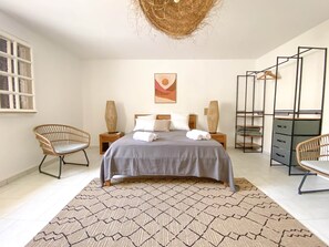 A bedroom with a bed, two nightstands, a chair, a wardrobe, and a hanging rack. - Villa Caméo • Grande villa familiale vue mer 180° (Le Gosier)