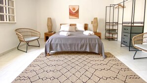 Una camera da letto con un letto, due comodini, due sedie, un armadio e un appendiabiti.