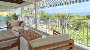 Un'area relax all'aperto con mobili in legno e vista sull'oceano.