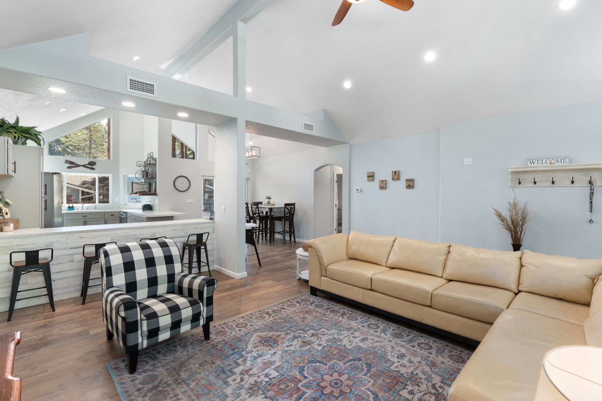 A modern living room with a beige sofa, a checkered armchair, and a patterned rug.