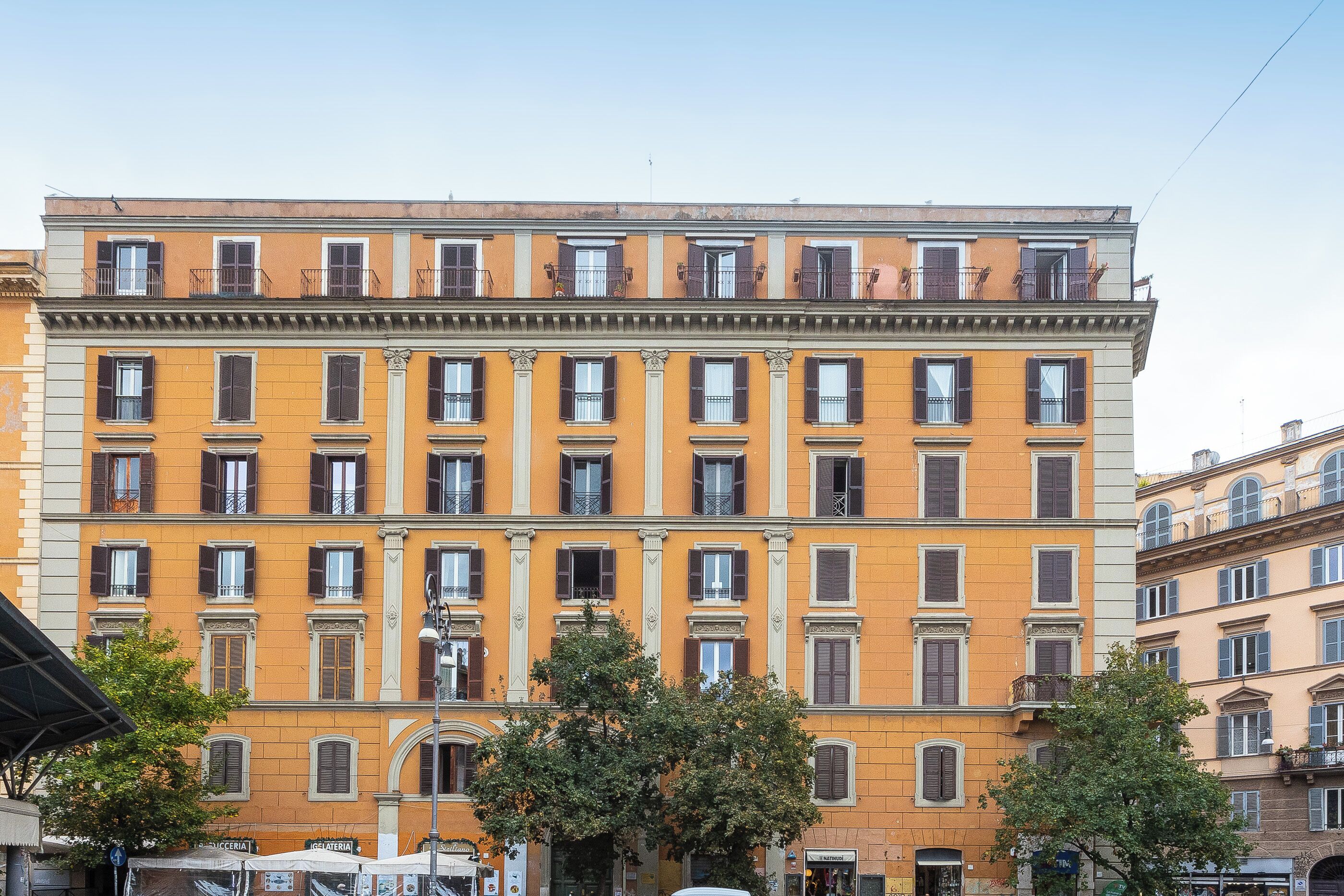 A multi-story building with a yellow facade, large windows, and balconies.