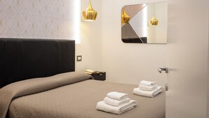 A modern hotel room with a bed, a nightstand, a mirror, and a wall-mounted light fixture. - Lovely New Home, Piazza San Cosimato! (Roma)