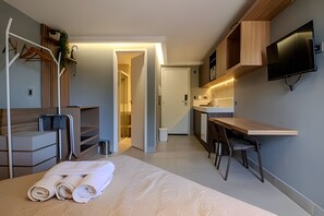 A modern hotel room with a bed, a desk, a TV, a wardrobe, and a bathroom. - Infinity At The Sea (João Pessoa)