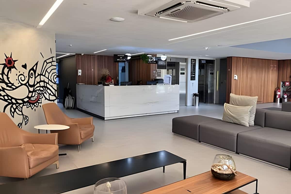 A modern reception area with a marble counter, leather seating, and a glass coffee table, and a unique wall art piece.