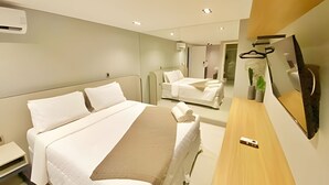A modern hotel room with a large bed, a bedside table, a TV, and a mirror. - Infinity At The Sea (João Pessoa)