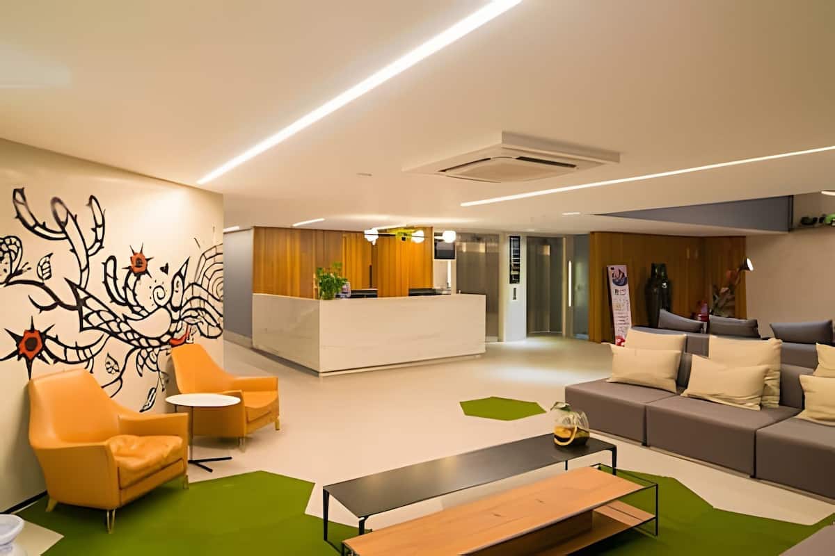A modern reception area with a reception desk, seating, and a green carpet.