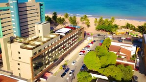 A high-rise hotel with a parking lot and a beach view. - Infinity At The Sea (João Pessoa)