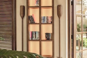 A bookshelf with books and two wooden paddles. - Namia River Retreat - Wellness Inclusive Resort (Hoi An)
