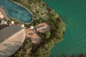 An aerial view of a resort with a swimming pool, lounge area, and a large building. - Namia River Retreat - Wellness Inclusive Resort (Hoi An)