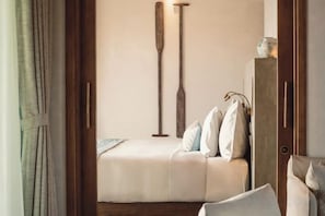 A bedroom with a bed, pillows, a nightstand, and a wooden floor. - Namia River Retreat - Wellness Inclusive Resort (Hoi An)