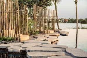 A stone pathway leading to a bamboo fence overlooking a body of water. - Namia River Retreat - Wellness Inclusive Resort (Hoi An)