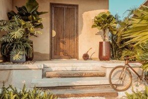 A house entrance with a wooden door, steps, and a bicycle. - Namia River Retreat - Wellness Inclusive Resort (Hoi An)