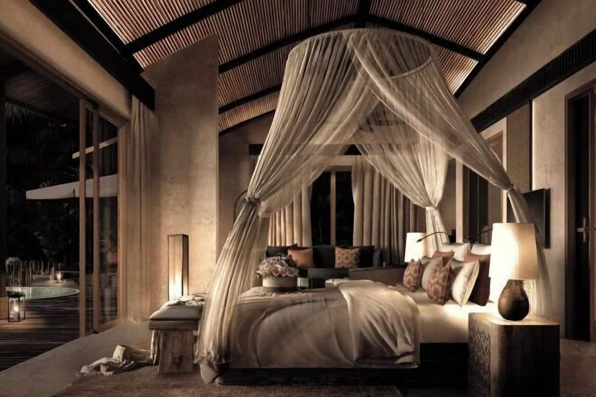 A bedroom with a canopy bed, bedside tables, and a view of the outdoors.