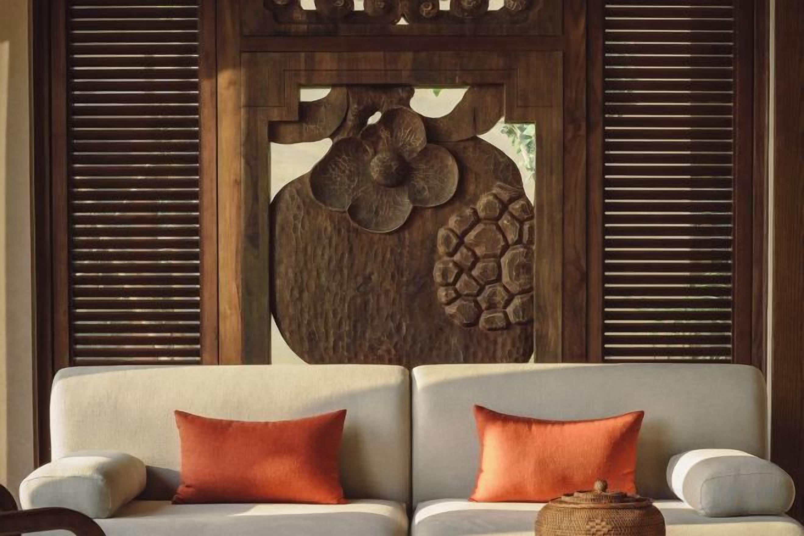 A sofa with two orange cushions and a woven basket.