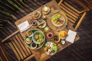 A wooden table with various dishes, including a plate of eggs, a bowl of salad, and a cup of coffee. - Namia River Retreat - Wellness Inclusive Resort (Hoi An)