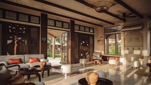 A spacious lounge area with a sofa, armchairs, and a coffee table. - Namia River Retreat - Wellness Inclusive Resort (Hoi An)