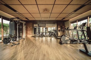 A gym with exercise equipment, large windows, and a wooden floor. - Namia River Retreat - Wellness Inclusive Resort (Hoi An)