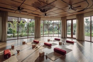 A spacious room with a wooden floor, large windows, and red seating areas. - Namia River Retreat - Wellness Inclusive Resort (Hoi An)