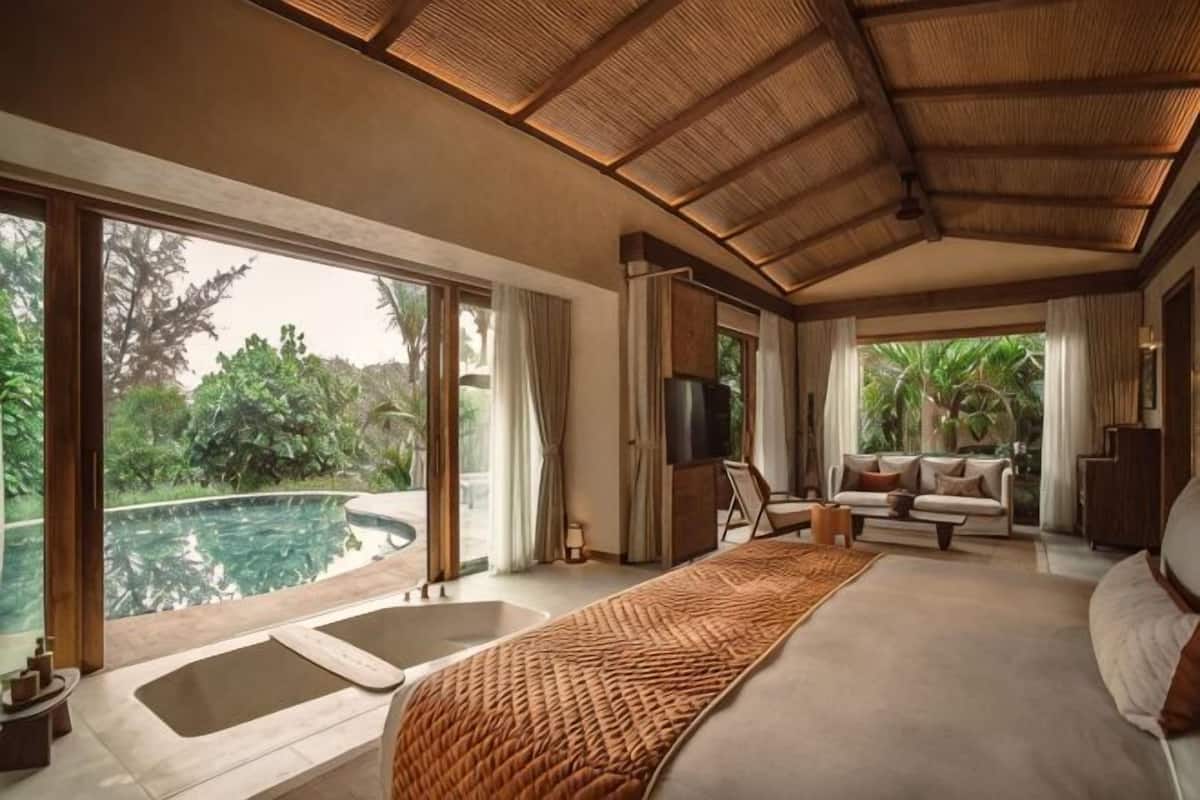 A bedroom with a large bed, a TV, a sofa, and a view of a swimming pool.