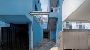 A narrow hallway with a geometric patterned floor, leading to a balcony with a white railing. - Hotel O 94843 Syariah Hj. Lilis Sukabumi (Sukabumi)